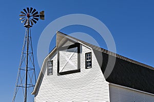 An old windmill and a white hip roofed barn