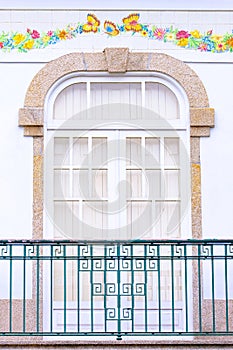 Old window with a balcony on a beautiful white house facade