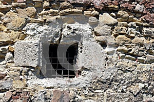 Old window with bars in a stone wall