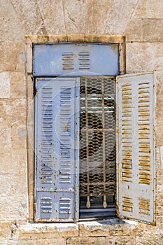 Old window with blue rusty metal blinds