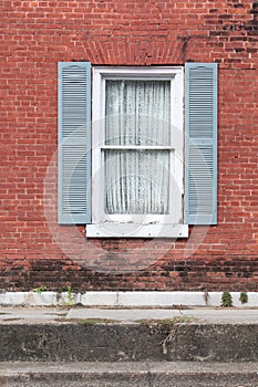 Old window and blue shutters in old brick wall