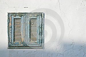 The old window with blue shutters on a white wall