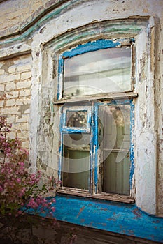 Old window with blue wooden frame with peeling paint. Rural house closeup