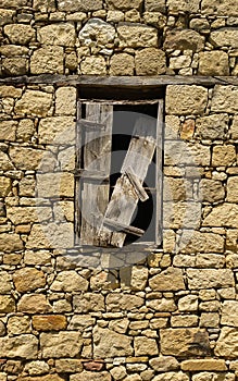 Old window with broken wooden shutter on a stone building