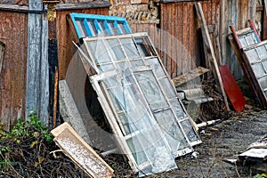 Old window frames and broken glass with boards in a heap of rubbish in the street