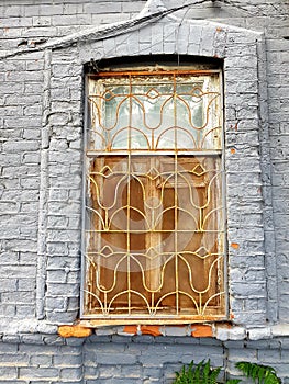 Old window with a grate in a stone wall