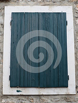 The old window with green - blue closed shutters on an old house. Vintage texture. Herceg Novi Montenegro, old stone