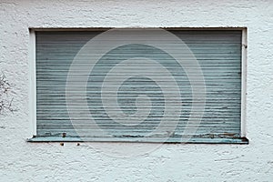 An old window on a house closed with a roller blind.