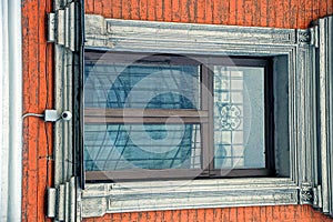 An old window with a lattice on a brick wall of an apartment house