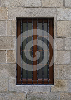 Old window with a metal grate in a stone wall