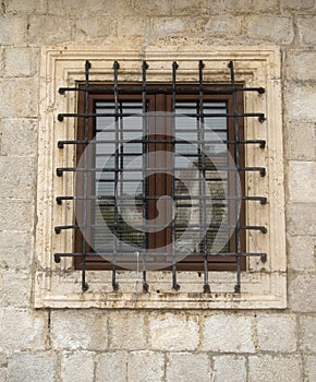 Old window with metal grill on stone facade in Montenegro