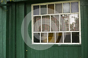 An old window in the village. Colored glass in the window frame. Facade of the house