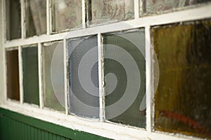 An old window in the village. Colored glass in the window frame. Facade of the house