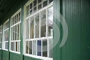 An old window in the village. Colored glass in the window frame. Facade of the house