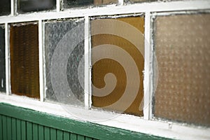 An old window in the village. Colored glass in the window frame. Facade of the house