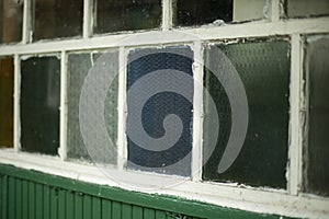 An old window in the village. Colored glass in the window frame. Facade of the house