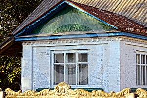 Old window on a white brick wall of a rural house with a wooden roof