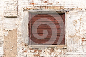Old window with wooden shatter on wall of abandoned building