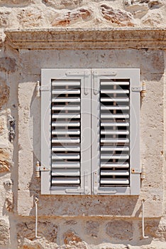 Old window with wooden shutters on yellow stucco wall and copy space Old Shutter windows with a flowers. Montenegro