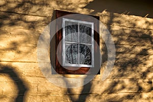 Old window on yel facade of wooden cottage