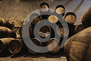 Old winery with wooden barrels full of port wine inside. Dark cellar for winemaking, Portugal