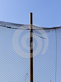 old wire fence made of thin wire against the blue sky