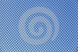 old wire fence made of thin wire against the blue sky