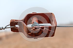 Old wire tensioner of a wire fence in a field closeup photo