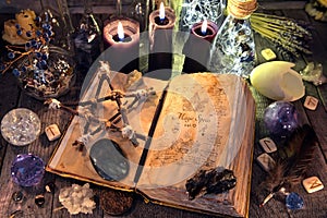 Old witch book with pentagram, black candles, crystals and ritual objects