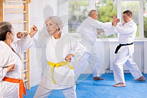 Old woman attendee of karate classes fighting with her opponent in sports hall