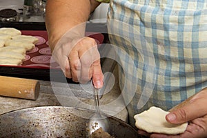 Old woman baking pies in her home kitchen. Grandma cooks pies. Home cooked food. omemade mold cakes of the dough in the ederly wom