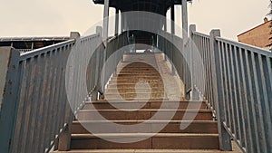 Old woman with black coat and hijab walking up the stairs of the footbridge