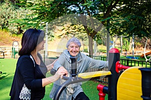 An old woman came to an outdoor fitness gym circle, accompanied by a caregiver.