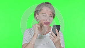 Old Woman Celebrating on Smartphone on Green Background