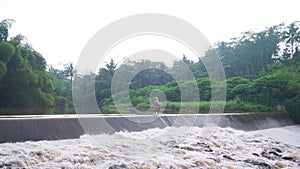 An old woman crosses a dam in Magelang, Indonesia