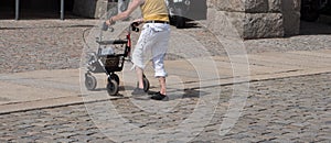 Old woman crosses a street with the rollator