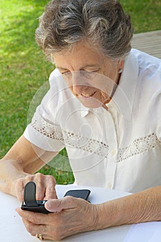 An old woman in dialling a telephone number on a smartphone photo