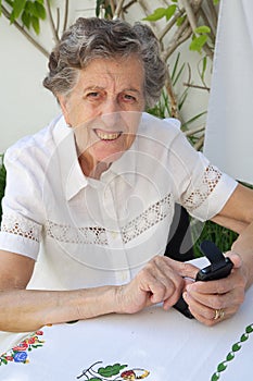 An old woman is dialling up a telephone number on her smartphone photo