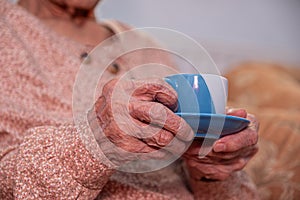 Old woman drinking coffee with smile on her face