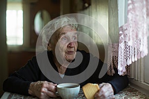 An old woman drinking tea with cookies at home