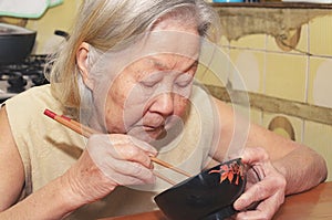 Old woman eating on a bowl