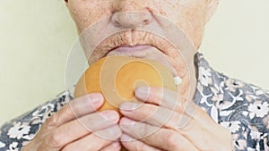 Old woman eating burger closeup, fast food