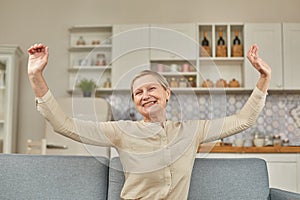 An elderly woman experiences the joy of being at home with her arms wide open. Happy pensioner concept