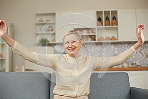 An elderly woman experiences the joy of being at home with her arms wide open. Happy pensioner concept