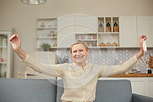 An elderly woman experiences the joy of being at home with her arms wide open. Happy pensioner concept