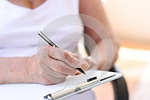 Old woman filling form in clinic or in hospice