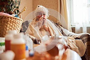 Old woman with flu blowing her nose in handkerchief