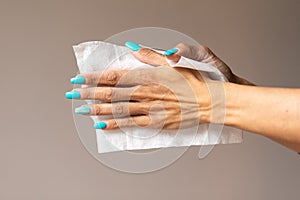 Old woman gently cleaning hands with wet wipes