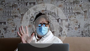 Old woman in glasses having a video call on the laptop smiling and talking happily indoors in a cozy apartment. doctor