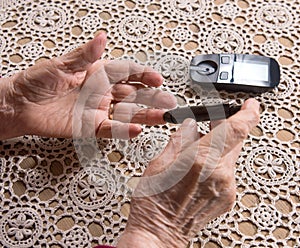 Old woman with glucometer checking blood sugar level